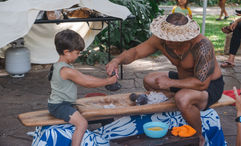 In a hands-on demonstration at Waimea Valley, a child learns how to pound taro into a paste, which is then used to make poi.