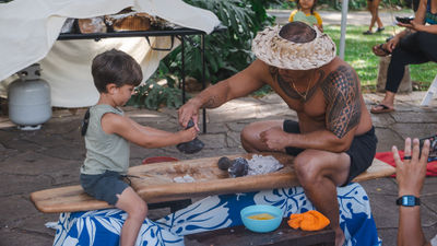 In a hands-on demonstration at Waimea Valley, a child learns how to pound taro into a paste, which is then used to make poi.