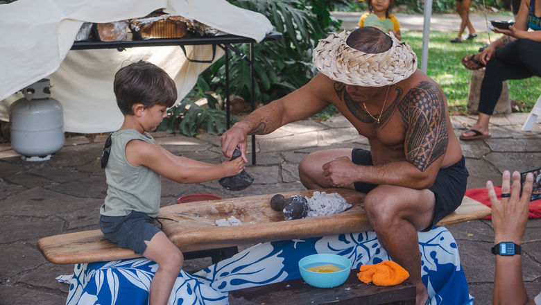 In a hands-on demonstration at Waimea Valley, a child learns how to pound taro into a paste, which is then used to make poi.