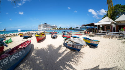 Fishing boats on the beach in Ocho Rios, with a cruise ship docked in the background.