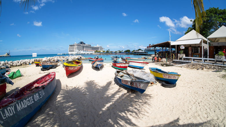 Fishing boats on the beach in Ocho Rios, with a cruise ship docked in the background.