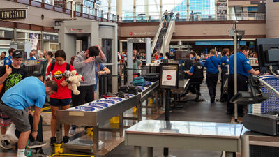 TSA agents managed a security checkpoint at Denver International Airport in 2019. The agency may be ending its policy that travelers remove their shoes at security.
