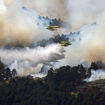 Two airplanes release water above a wildfire in Guadalajara, Spain.