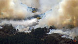 Two airplanes release water above a wildfire in Guadalajara, Spain.