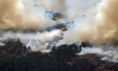 Two airplanes release water above a wildfire in Guadalajara, Spain.