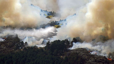 Two airplanes release water above a wildfire in Guadalajara, Spain.