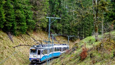 A blue Zugspitze cogwheel train traveling through the Alps foothills near Eibsee, Germany.