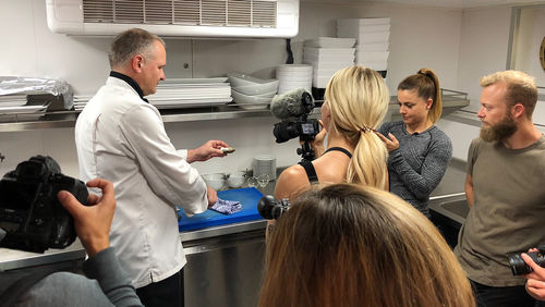 Ence (with the camera), fitness guru Christmas Abbott (to Ence's right) and Bledsoe (to the right of Abbott) watch as the Amadeus Provence chef shucks local oysters.