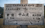 A rustic sign on the Nakasendo in English and Japanese points walkers toward Tsumago and Nagiso.