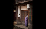 A kimono-clad woman pears in the entrance of an establishment along a pedestrian street in the historic Higashichaya Old Town district of Kanazawa.
