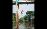 Boys take turns jumping off a bridge in Chau Doc.