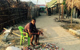 A Corbisky Island resident flattens cans by lifting and dropping the head of a sledge hammer in preparation for recycling.