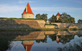 Another view of Saaremaa's Episcopal Castle, at right, and an associated tower, both reflected in the castle's moat.