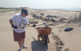 Jackie Amari, of American Express, shovels sand to clear a path near the beach at Fort Tilden.