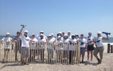 Travel Weekly Editor in Chief Arnie Weissmann and members of the snow-fencing project team stand next to a completed portion of fence at Fort Tilden.