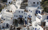 The iconic view of houses cascading down the side of a Santorini cliff in Oia, a small village at the tip of the crescent-shaped island.