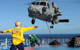 A crewman from the aircraft carrier Ronald Reagan signals pilots of a helicopter to lift off from the deck of the Carnival Splendor.