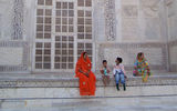 An Indian family take a break from sightseeing under one of the Taj Mahal's white, massive outer marble niches, adorned with patterns of inlaid semi-precious stones.