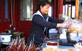 Visitors can purchase a marinated, fried swallow on a stick, a popular Zhangjiajie delicacy, at this vendor's location in the Yuanjiajie Scenic Area.