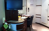 Flat screen TVs and a desk with ample drawer space and a leather chair occupy the sitting area of Category A cabins on Wind Surf.