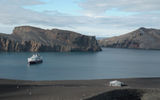 The Fram at Deception Island, in front of the narrow opening, called Neptune's Bellows, into the flooded caldera of an active volcano, as seen from the top of a slope on the caldera’s rim.