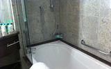 A full-size tub, along with a shower, is surrounded by natural-tones of marble in a Concierge stateroom.