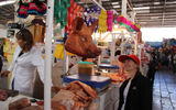 Inside the market, General Tours' Beth Karlicek inspects a pork vendor's stand.