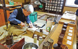 An artisan at a museum showcasing the history of cherry-tree bark crafts.