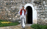 A host, in traditional dress, emerges from the Mazrekaj family kulla. The house was restored to receive tourists and locals for lunches and other events.