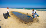 A cleanup crew rakes tar balls on a stretch of Gulf Coast beach earlier this summer.