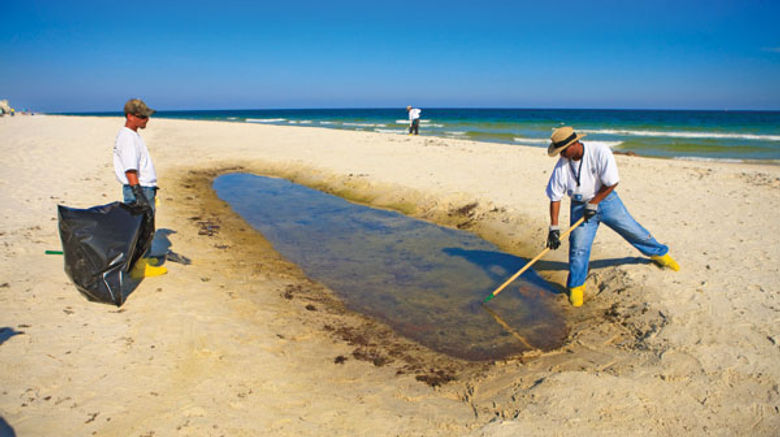 A cleanup crew rakes tar balls on a stretch of Gulf Coast beach earlier this summer.