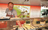 A cheese vendor reaches for blue cheese in his case at the market.