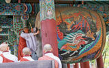 A Haeinsa monk, using a very large hanging drum, calls fellow Buddhists to an evening service.