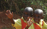 Two schoolgirls wave to passing tourists near the entrance to Ziwa Rhino Sanctuary.