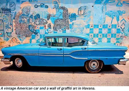 A vintage American car and a wall of graffiti art in Havana.