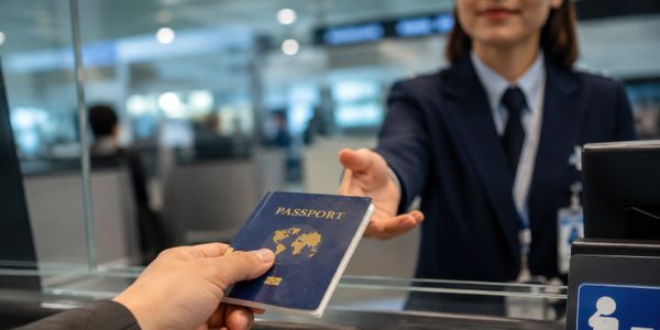 A blue passport is handed over at an airport counter.