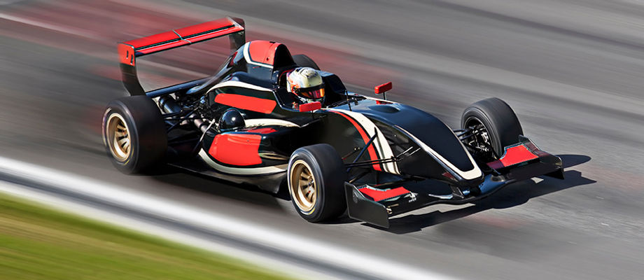 A black racecar speeds on a track with red and white accents.