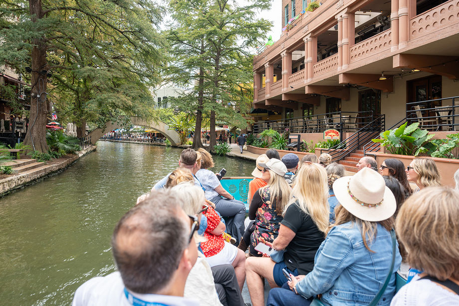 A passenger boat tours along the San Antonio River.