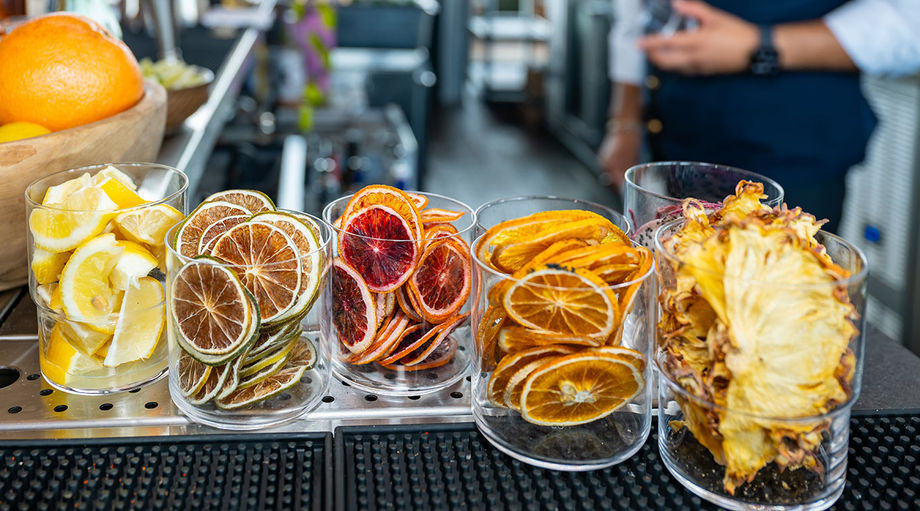 Jars of dried citrus slices sit on a metal bar counter.