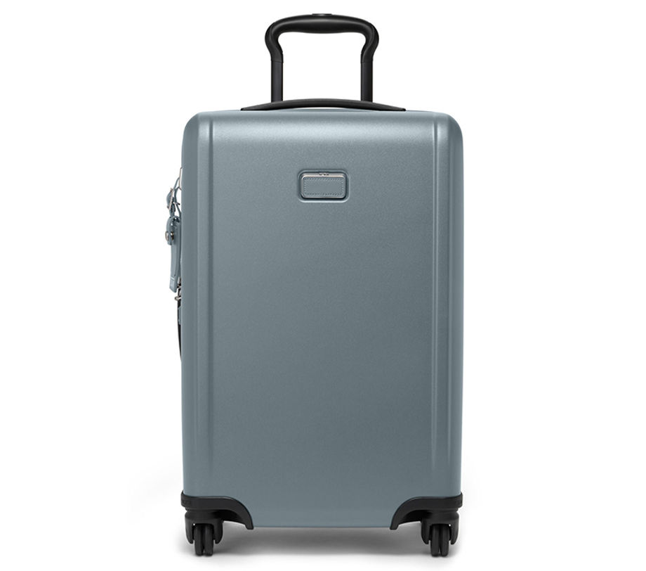 A silver TUMI hard-shell suitcase stands upright with wheels.