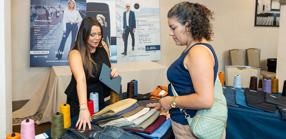 A representative from Delta Blue Jeans helps an event attendee choose the perfect style of jeans.