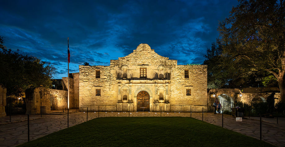 A historic stone building lit at dusk with a central arched entrance.