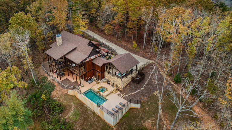 Modern house with a pool nestled in a forest at sunset.