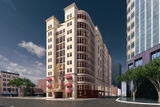 A beige multistory building with a rounded corner and red awnings on a sunny urban street.