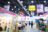 A busy blurred trade show hall with attendees walking between booths.