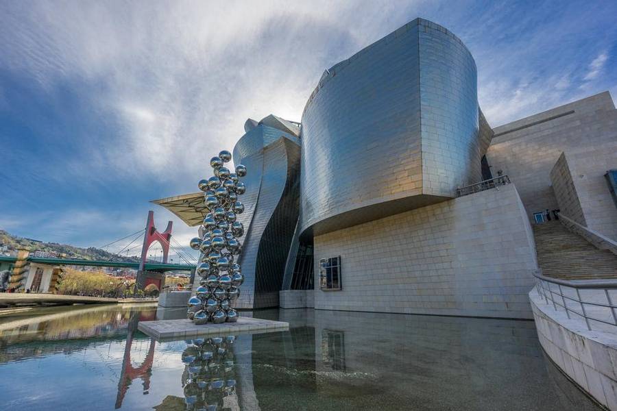 silver postmodern building with balls statue in the front