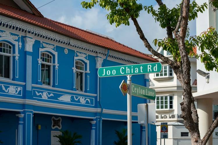 Joo Chiat Road street sign against blue shophouse