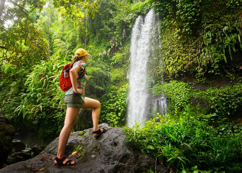 Young woman backpacker looking at the waterfall in jungles