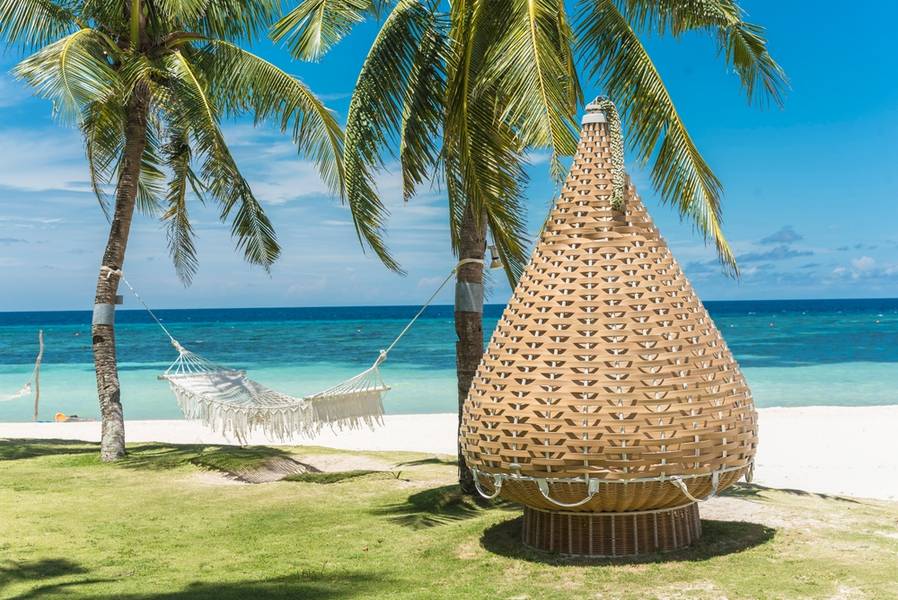 A hammock sofa chair made with rattan near the coast. At a luxury resort in Dumaluan Beach, Panglao Island, Bohol, Philippines.