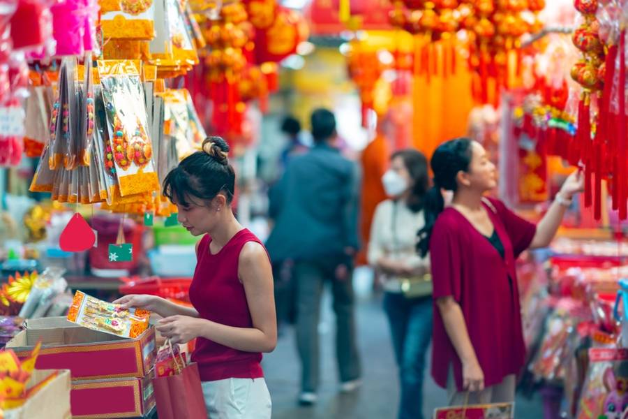 Asian woman mother and daughter holding shopping bag during buy home decorative ornament for celebrating Chinese Lunar New Year festival at Bangkok Chinatown street market.